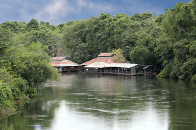 Houses by lake and trees against sky