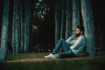 Young woman sitting on tree trunk in forest
