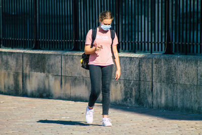 Full length portrait of teenage girl standing against wall