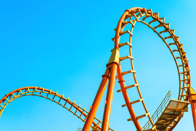 Low angle view of ferris wheel against clear blue sky