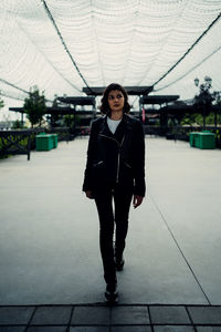 Portrait of young woman standing against built structure