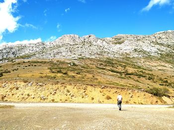 Rear view of man walking on mountain against sky