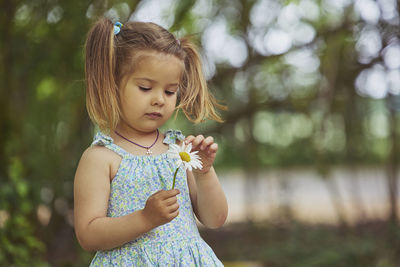 Portrait of cute girl blowing bubbles while standing outdoors