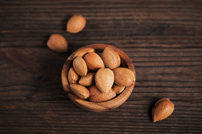 Pile of almond nuts in a bowl on a dark wooden background