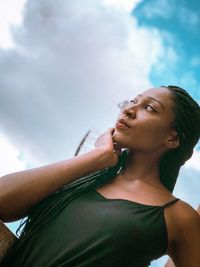 Low angle view of young woman looking away against sky