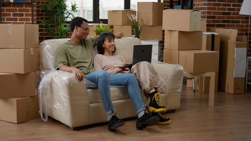 Happy couple with laptop sitting on sofa