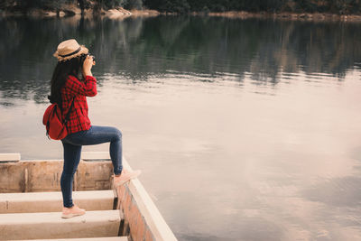 Young woman standing on boat moored in lake