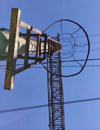 Low angle view of electricity pylon against clear blue sky