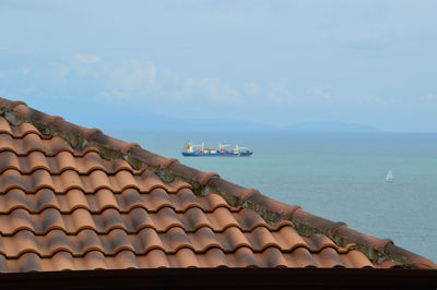 Roof of building by sea against sky