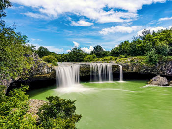 Long exposure photo of waterfall, pool, river, nature, landscape, blue sky with clouds.