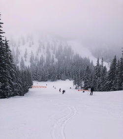 People on snow covered field against sky