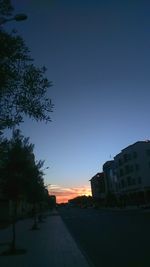 Road in city against sky at sunset