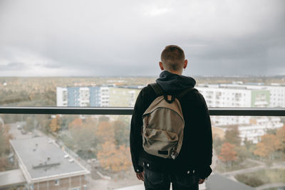 Rear view of man looking at cityscape against sky