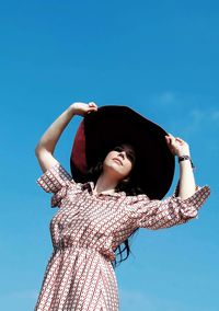 Low angle view of woman against blue sky