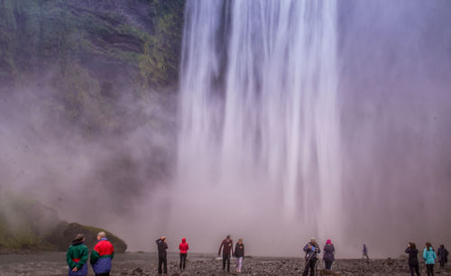 People standing by waterfall