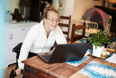 Portrait of smiling young woman using phone at home