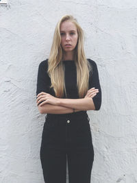 Portrait of a beautiful young woman standing against wall