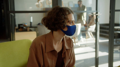 Side view of young woman with protective mask in office