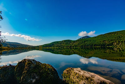 Scenic view of lake and mountains against blue sky