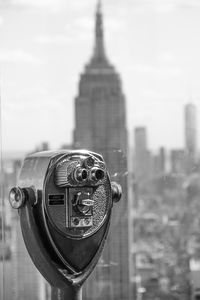 Close-up of coin-operated binoculars against buildings