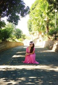 Portrait of woman with pink umbrella against trees