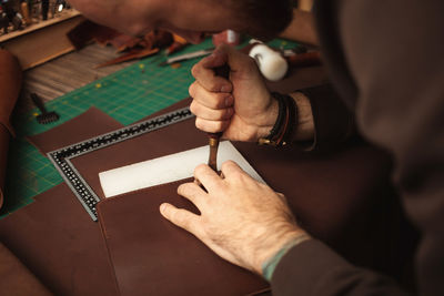 Processes edges with hot tool. tanner makes leather purse. diy instruction. eco 