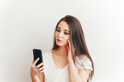 Beautiful young woman using smart phone against white background