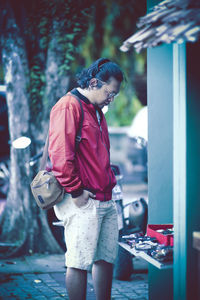 Man looking down while standing on footpath outdoors