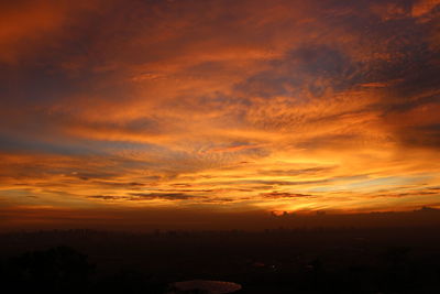 Scenic view of silhouette landscape against dramatic sky during sunset