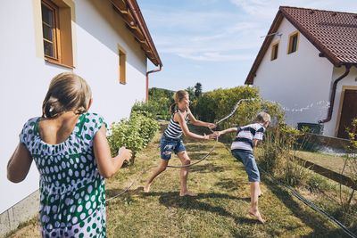 Girl spraying water on brother in yard