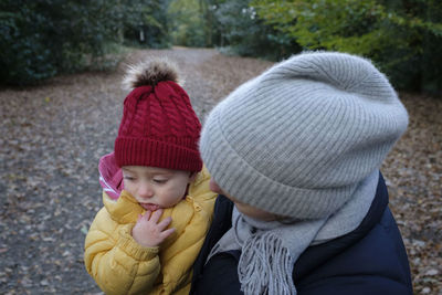 Close-up of woman holding crying son on road