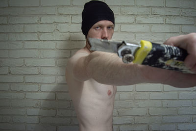 Portrait of young man standing against wall