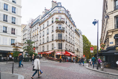 People walking on street amidst buildings in city