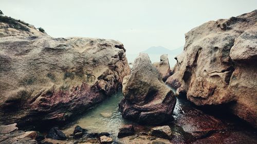 Rock formations in water against clear sky