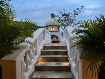 Staircase by palm trees against sky