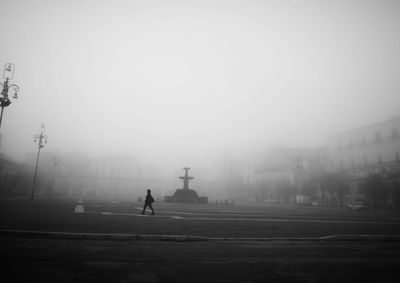 People walking on road in city against sky