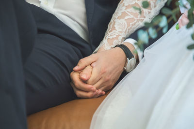 Midsection of bride and groom holding hands during wedding