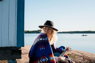 Portrait of woman sat playing the guitar wrapped in pendleton