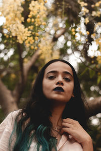 Portrait of beautiful young woman against trees