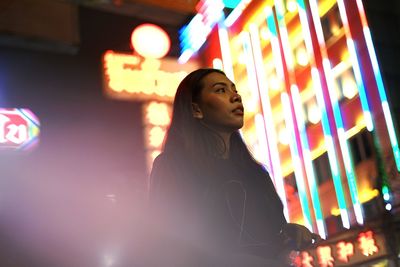 Woman looking away in illuminated city at night