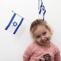 Close-up of cute girl looking away by israeli flag against white background