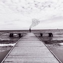 Pier on sea against cloudy sky