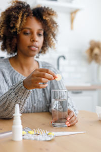 Portrait of young woman using mobile phone while sitting on table