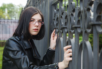 Portrait of young woman standing against black background