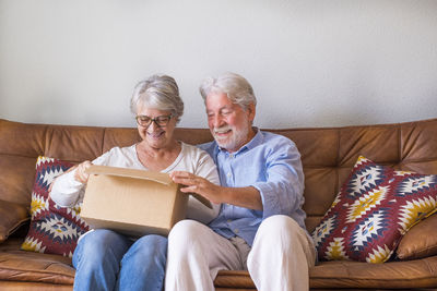 Smiling senior couple looking inside cardboard box
