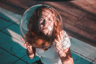 Close-up of young woman wearing glass container outdoors