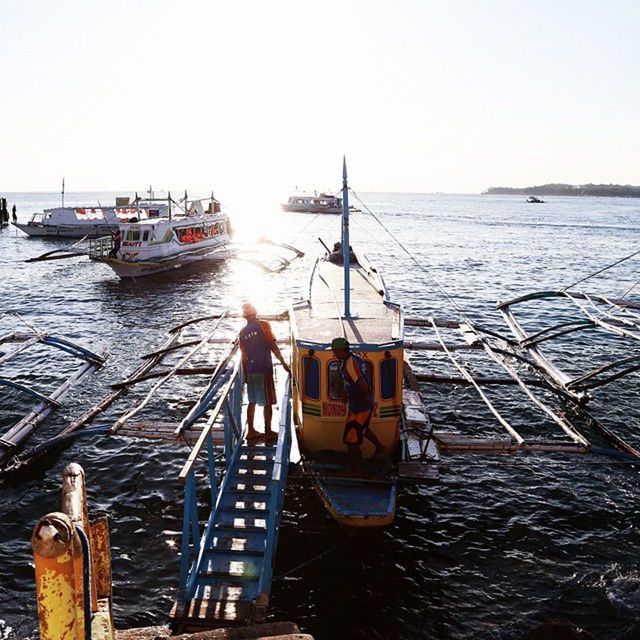 nautical vessel, water, sea, boat, transportation, mode of transport, moored, men, lifestyles, horizon over water, leisure activity, clear sky, sky, nature, travel, pier, outdoors, beauty in nature