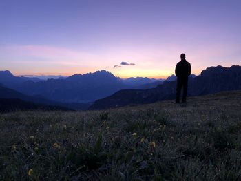 Rear view of silhouette man standing on field against sky during sunset