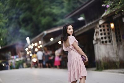 Portrait of young woman standing on road