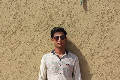 Portrait of young man wearing sunglasses standing on beach